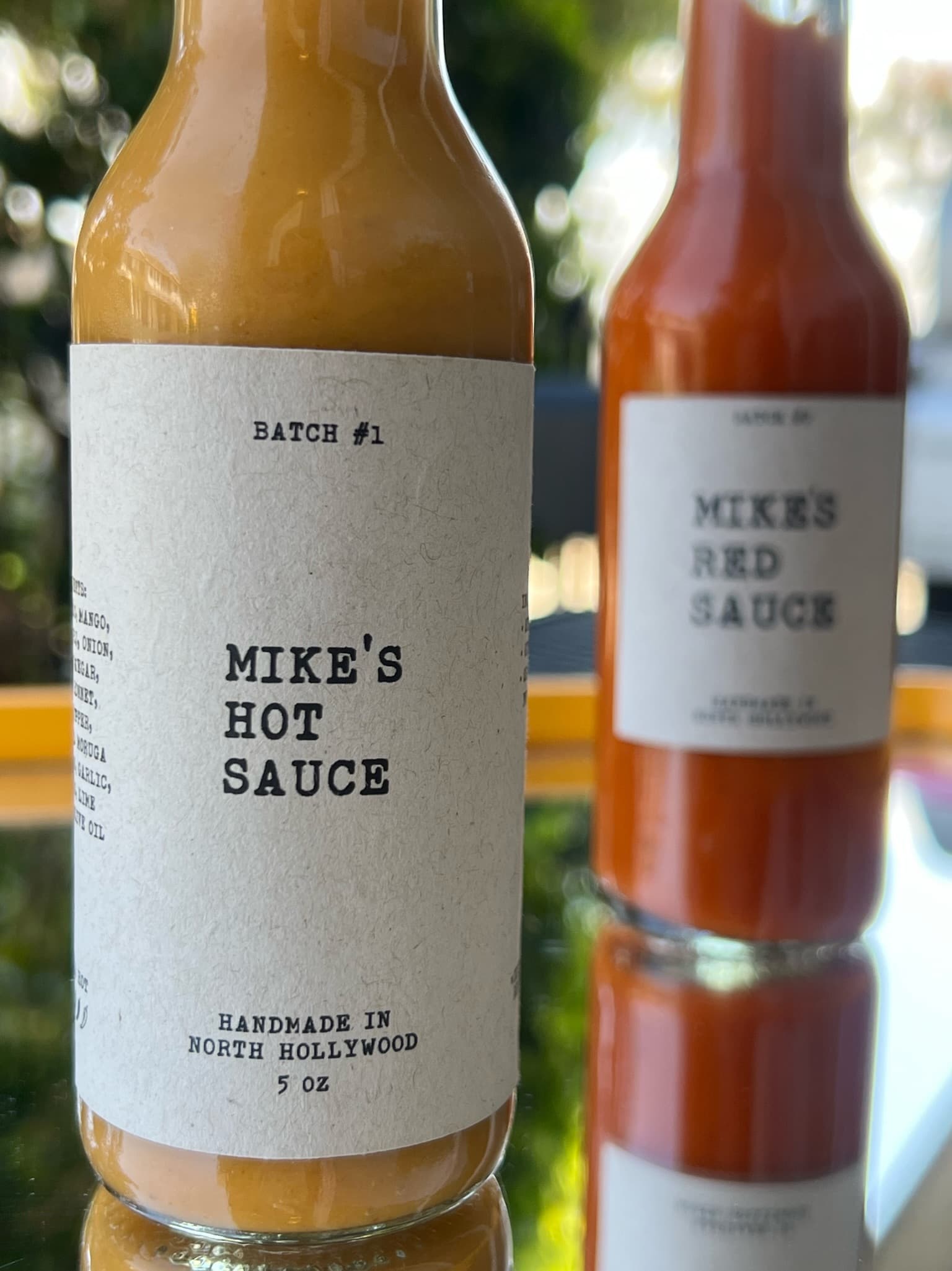 Mike's Hot Sauce Batch #1 bottle, foreground; Mike's Red Sauce bottle, background.